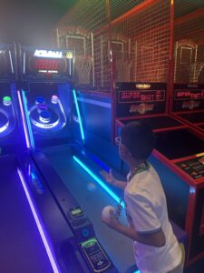 A boy playing a game of ski ball in an arcade.