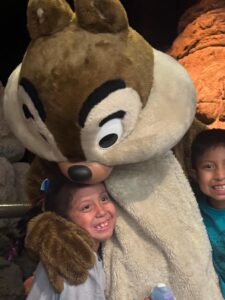 A girl being kissed on top of the head by an oversized chipmunk.